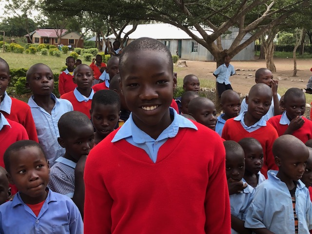 Smiling student in school uniform with classmates outdoors